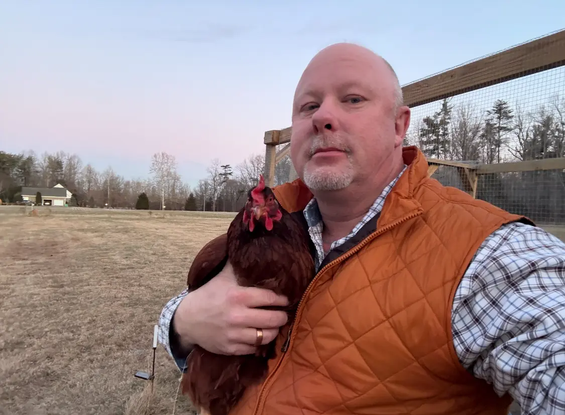 James Kaufer outdoors holding a chicken at his Southern Indiana home